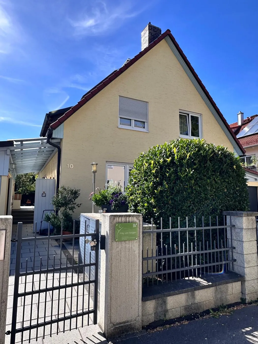 Das gelbe Haus mit Praxisschild am Eingangspfeiler, Robert-von-Haug-Straße 10