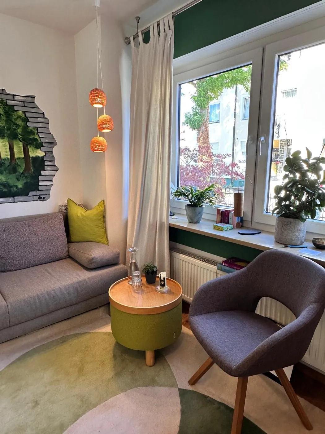 Praxisraum mit Sofa, Sessel und Blick ins Grüne
